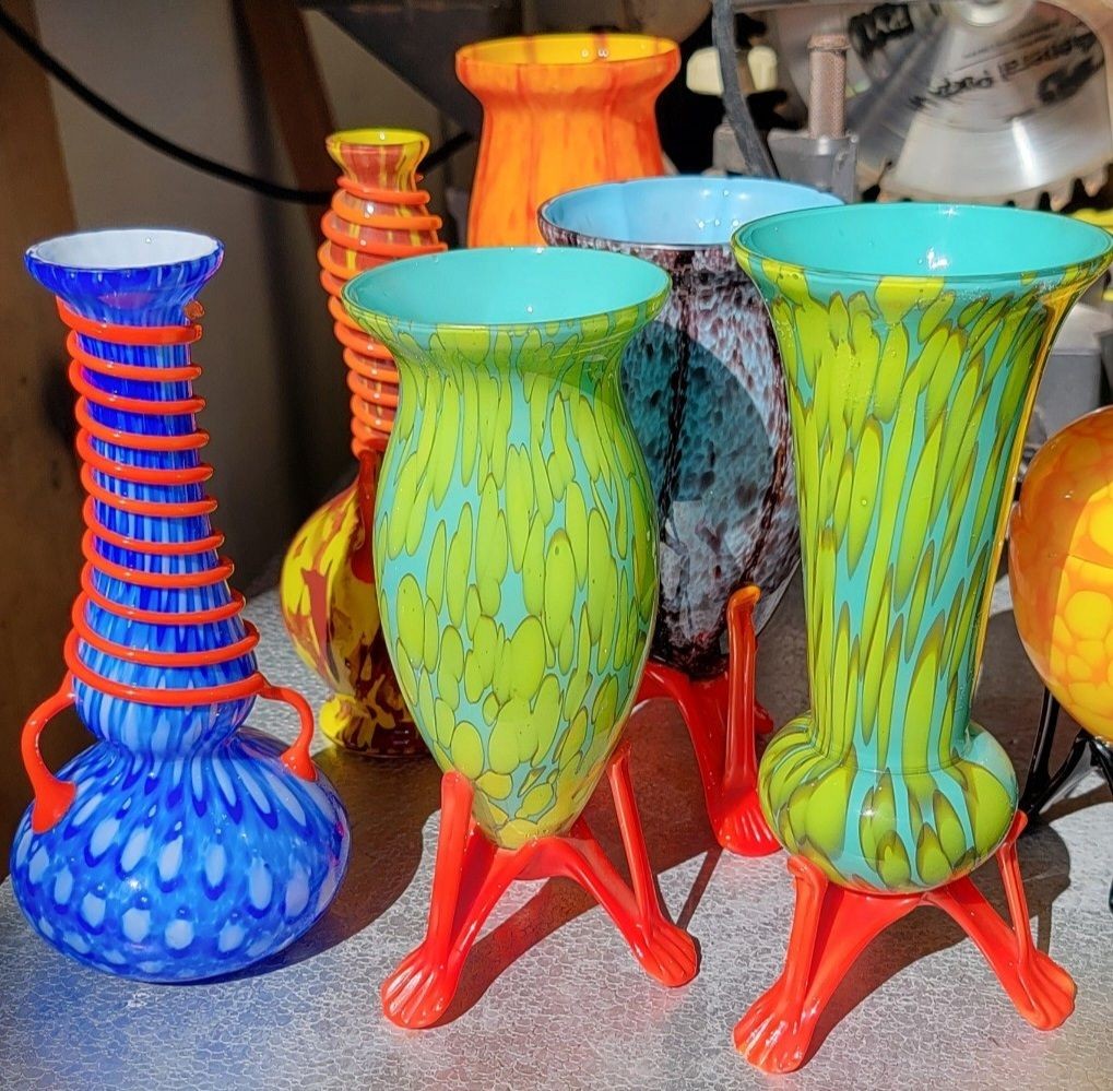 Colorful, intricately designed glass vases with vibrant patterns, displayed on a metallic surface.